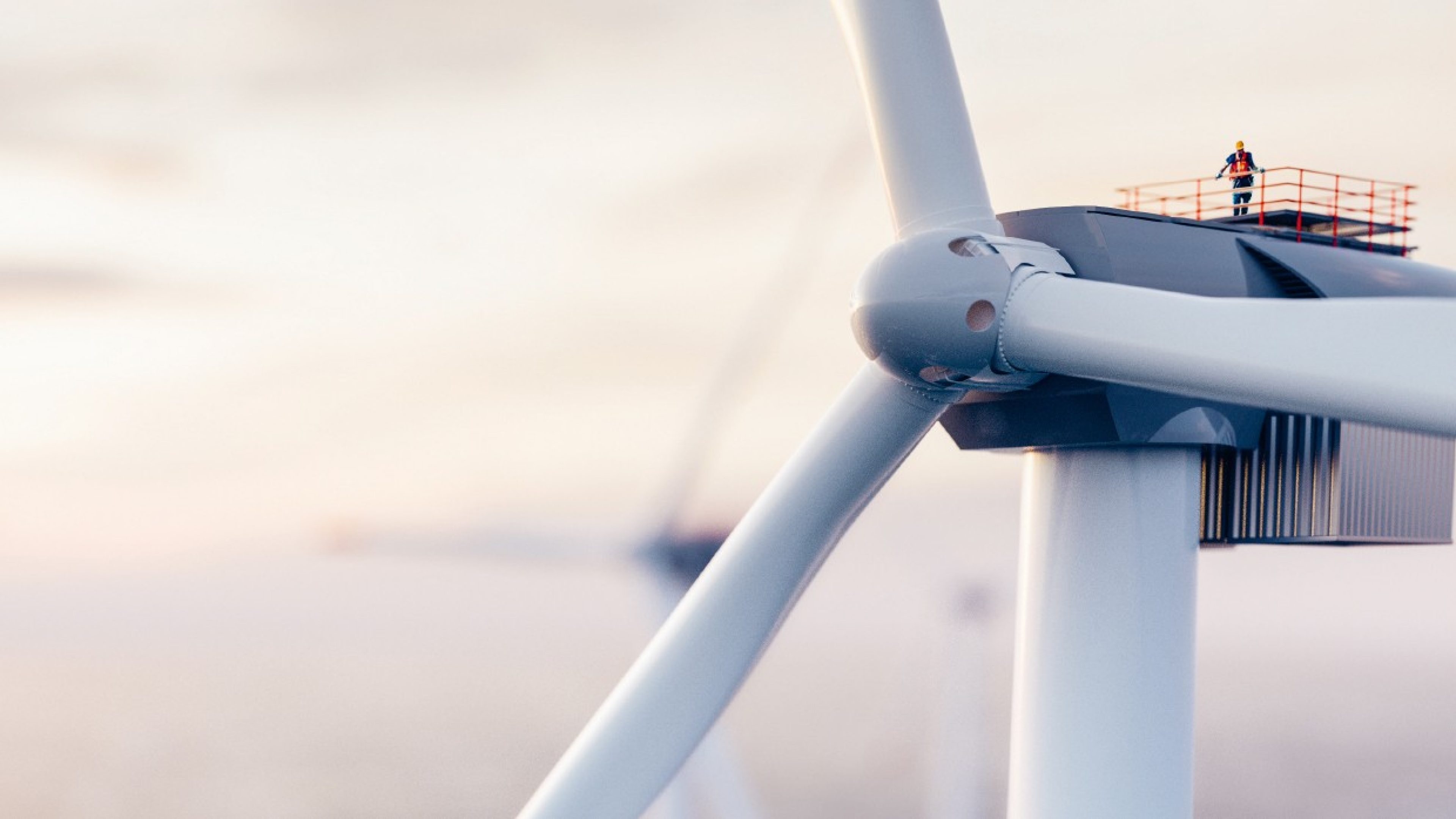 Man standing on platform next to rotor of a large wind power windmill